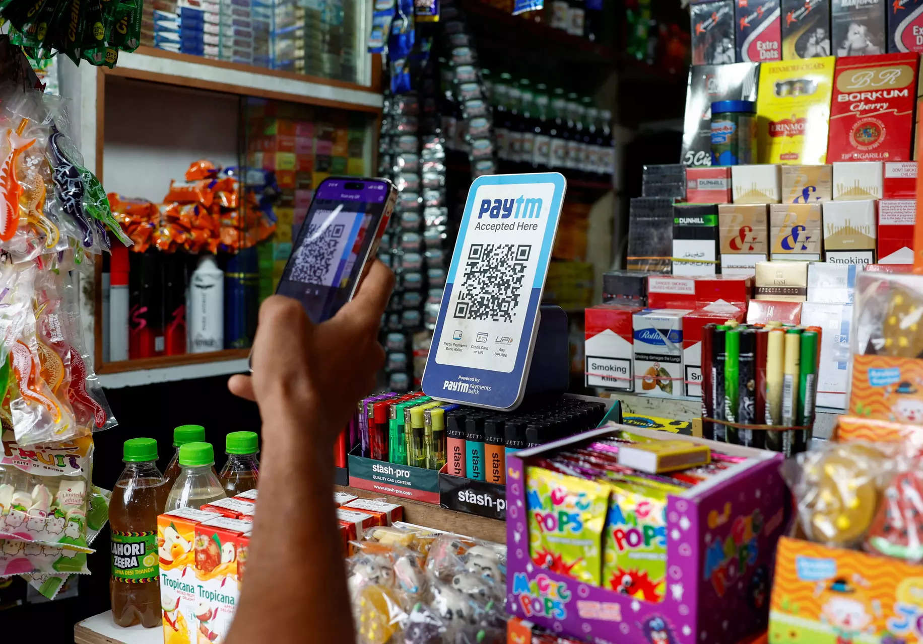 A man uses his phone to scan a QR code of the digital payment app Paytm after purchasing a cold beverage at a shop in Kolkata